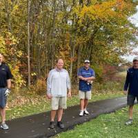 Four alumni standing by golf course
